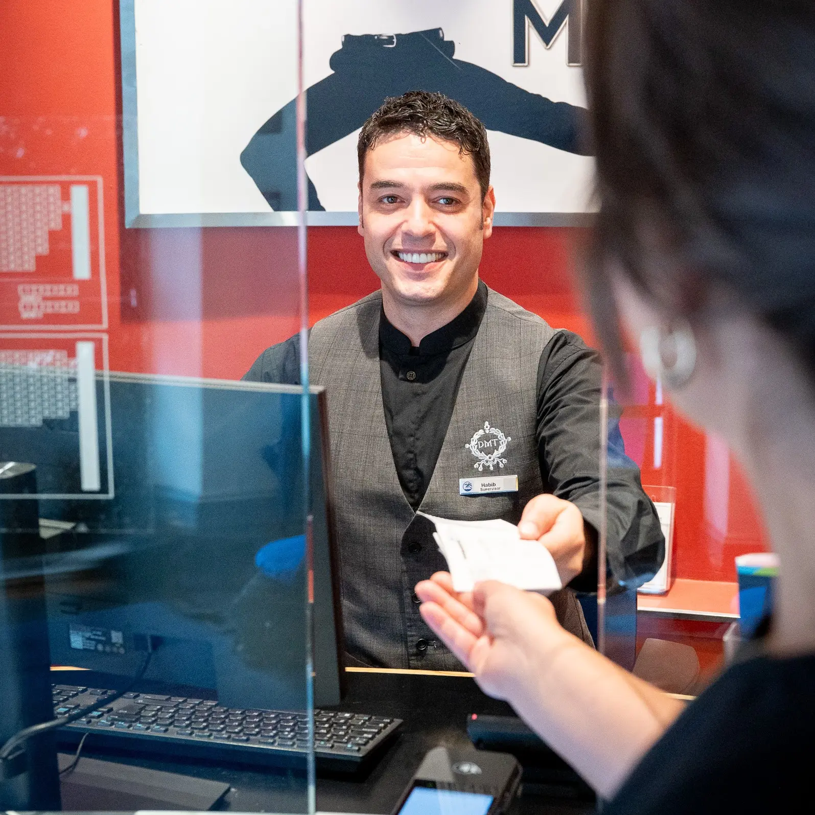 Person behind a box office handing a ticket out