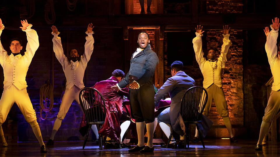 Simon Anthony Rhoden as Aaron Burr and Hamilton Company. Photo by Danny Kaan.